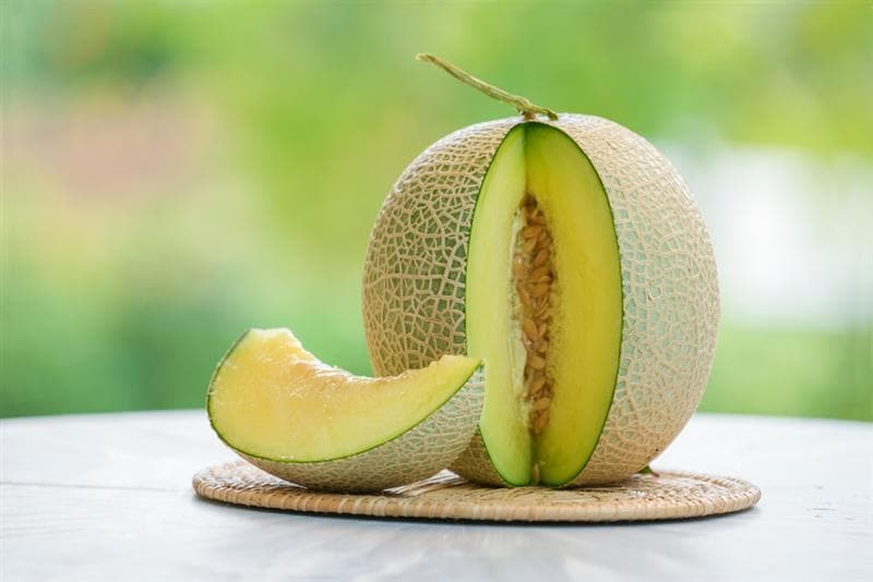 Muskmelon cut and rested on wooden plate